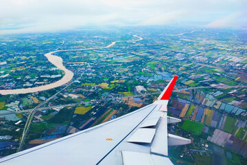Beautiful aerial view of Bangkok, Thailand from window of a plane descending for landing overlooking the Chao Phraya River. Green areas of the city and roads. Airplane travel photography ideas