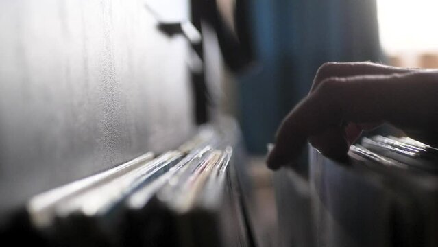Male hands going through vinyl records, close up view. Audio music vintage records, browsing the records in LP collection.