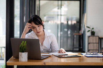 Businesswoman working with laptop while sitting in desk, Asian business woman doing paperwork, tax, financial economy report analysis.