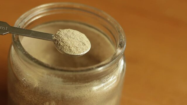 A quarter teaspoon of finely white ground pepper powder is being scooped with stainless steel measuring spoon cup