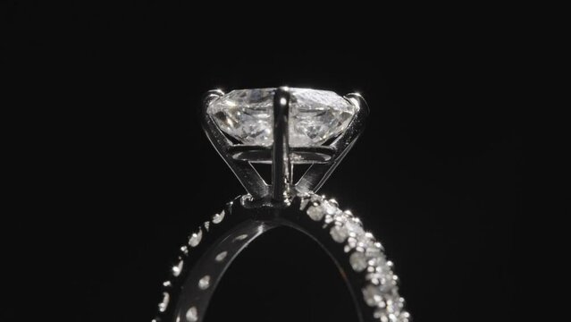 Close up, diamond ring slowly rotating against black studio background