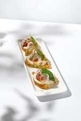 Aesthetic composition with tomato bruschetta on white background with harsh shadows. Italian bruschetta with tomatoes and cheese on fine dining in summer. Elegant menu concept.