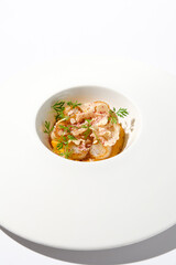 Appetizer with roasted sea scallop and cauliflower. Creamy risotto with scallops and vegetables. Grilled sea scallops in white ceramic plate with harsh shadows. Seafood menu. Summer food.