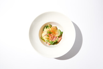 Elegant salad with crab meat, espuma sauce and lettuce on white table with harsh shadows. Green...