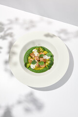 Creative dish from roasted chicken and broccoli puree on white plate. Sliced baked chicken with vegetables and creamy espuma in summer menu.