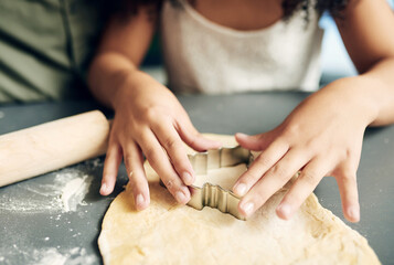 Family, hands baking and christmas tree cookies being made with a cutter while bonding and learning. Sweets, dessert and biscuit treat being baked with dough by a child and her parent at xmas