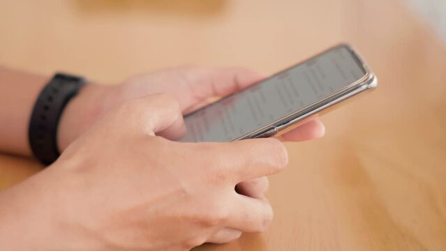 Hand of woman using application on smartphone she reading mail on social media at wooden teble, finger of happy female slide modern mobile phone screen, online internet searching