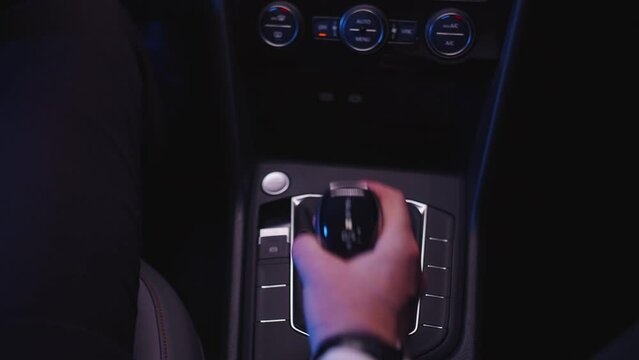 a man with a watch on his arm switches an automatic transmission