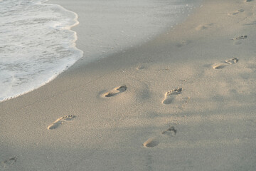 Fototapeta na wymiar Footprints on the sandy coast of the sea. Relaxation concept. Background, soft light, front view