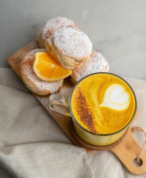 Closeup of baked British scones with turmeric latte on kitchen wooden board