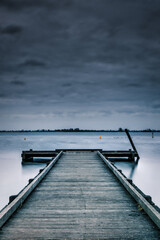 wooden pier in a lake with clouds