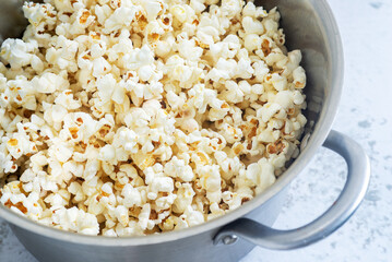 homemade salted butter popcorn in metal pot on marble background