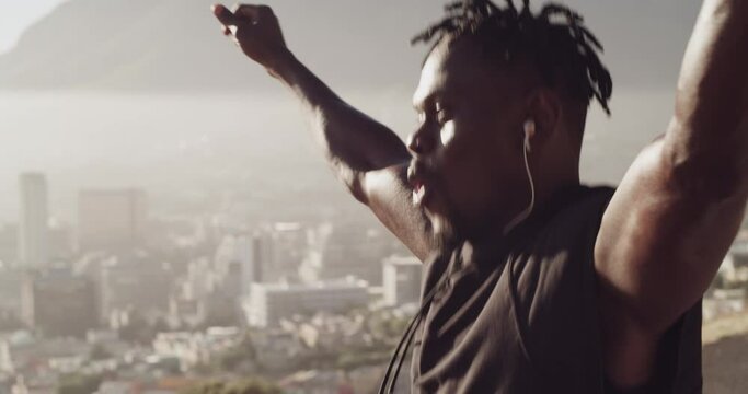 Fitness, celebration and man running in city happy to reach training goal, achievement and motivation. Sports, exercise and black man with success, freedom and wellness with headphones on mountain