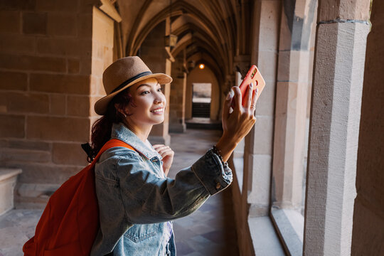 Happy girl traveler and tourist taking selfie photos and walks in the hall of an ancient monastery or the courtyard of the cathedral