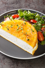 Lunch or dinner egg dishes is the famous Poulard Omelette with vegetables salad closeup on the plate on the dark background. Vertical