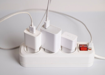 Many chargers are connected to an electrical outlet on a white background.
