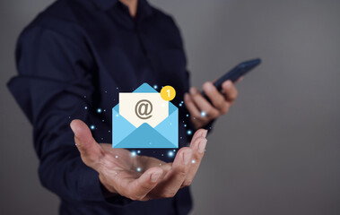 Hand of Businessman holding Email icon and mobile smartphone. Symbol marketing or newsletter concept.
