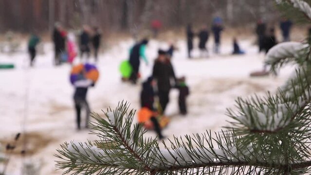 Children ride downhill in winter and climb the slope in defocus. Happy friends, holidays, winter fun, snowy mountain slopes. Video, footage for the background, intro, titles. UHD 4K.