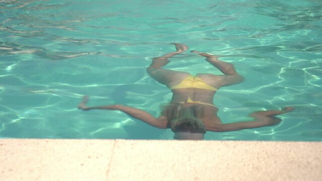 Attractive woman swims underwater in an outdoor summer pool