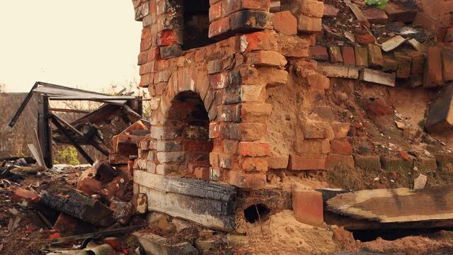 A destroyed stove without a red brick chimney, the remains of a burnt house. An abandoned building, a consequence of the war, bombing, missile strikes. Ruins, people in evacuation. UHD 4K.