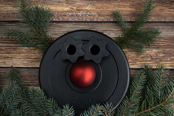 Dumbbells barbell weight plate disc shaped as a reindeer. Christmas tree branches as antlers, red...