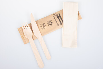 wood tableware wooden fork knife and recycled napkin on recyclable packaging isolated on white...