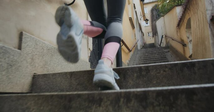 Woman Jogging And Running Up Stairs In An Alley At An Historic Town, Low Angle Tracking Shot Seen From Behind