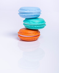 Three macarons of three different colors non-symmetrically stacked, on a white background