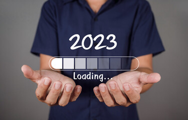 Man hand holding taps a virtual download bar. Turning the year 2022 to 2023.