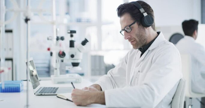 Headphones, science and technology of scientist in laboratory listening to music for focus, inspiration and innovation writing notes. Medical engineer with notebook and audio sound for research work