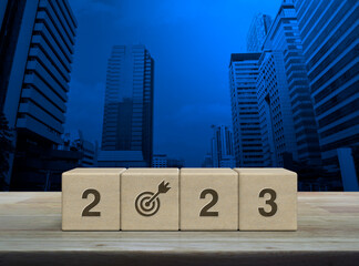 2023 letter with goal icon on wood block cubes on wooden table over modern office city tower and skyscraper, Happy new year 2023 success concept