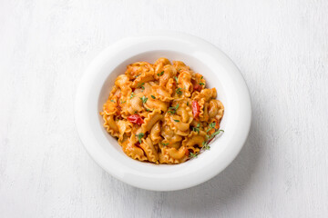 Simple pasta with tomato sauce sprinkled with fresh thyme in a white plate on a light gray background, top view, flat lay. Delicious homemade food