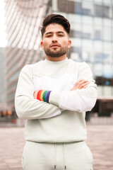 portrait of young hispanic man with lgbt bracelet and crossed arms , proud concept