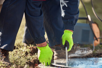 Construction worker handyman working on a sewer manhole lid.