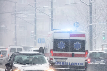 911 ambulance van rushing through traffic during heavy winter snowfall conditions.