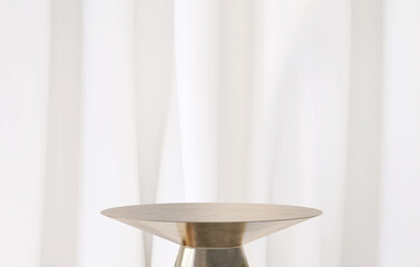 Modern and luxury gold colored round shiny pedestal podium steel in sunlight from window with white curtain in background for product display - obrazy, fototapety, plakaty