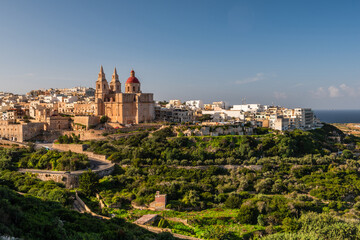 Fototapeta na wymiar Il-Mellieha, Malta - Mellieha town at sunny day with Paris Church on hill top, bay and sea in background