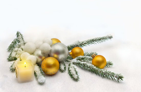 Christmas decoration. Christmas candle, white, yellow and silver balls, Christmas tree branches on snow, covered snow with space for text