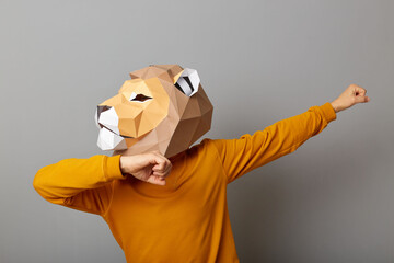 Horizontal shot of strong man with lion mask with wearing casual style orange jumper posing...