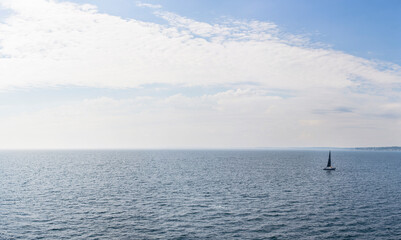 Segelboot auf offener See. Panorama über Ocean mit einsamen Segelboot am Horizont.
Sailboat on the open sea. Panorama over ocean with lone sailboat on horizon.