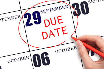 Hand writing text DUE DATE on calendar date September 29 and circling it. Payment due date