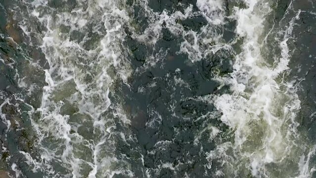 Muddy Water. Dirty Water Flow. Industrial wastewater and foam. Discharge of polluted wastewater into the river. Hazardous waste water. Drone top view shot. Slow motion 120 fps, ProRes 422 video