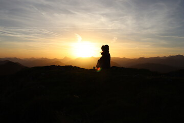 young woman is sitting on a mountain during sunrise 