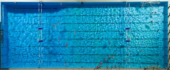 Aerial drone top view of swimming pool with athletes training water polo