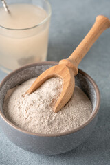 Psyllium husk powder in bowl close-up and glass with of water soluble fiber for intestinal, gray...