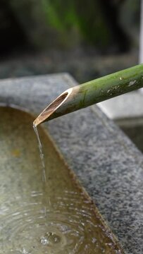 Shrine on a rainy day, water flowing from a bamboo tube into a water