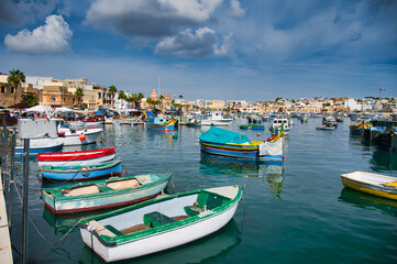 Fototapeta na wymiar View of Traditional fishing boats Luzzu in the Ancient Mediterranean Village of fishermen in Marsaxlokk, Malta