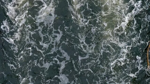 Muddy Water. Dirty Water Flow. Industrial wastewater and foam. Discharge of polluted wastewater into the river. Hazardous waste water. Drone top view shot. Slow motion 120 fps, ProRes 422 video