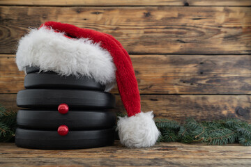 Obraz na płótnie Canvas Dumbbells weight plates in red Santa Claus Christmas hat, stacked on top of each other in shape of snowman. Gym holiday season winter composition. Fitness workout training concept with copy space.
