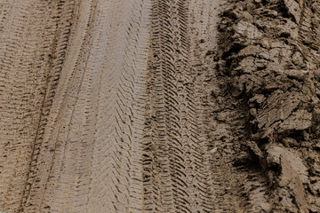 Tire tracks from the wheels of passing cars in the wet, softened ground on a muddy rural road.Multi layers of tire tracks print on dirty brown soil.Wheel marks of cars and trucks on countryside route.